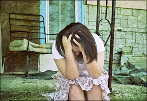 Depressed woman hunched over holding her head.